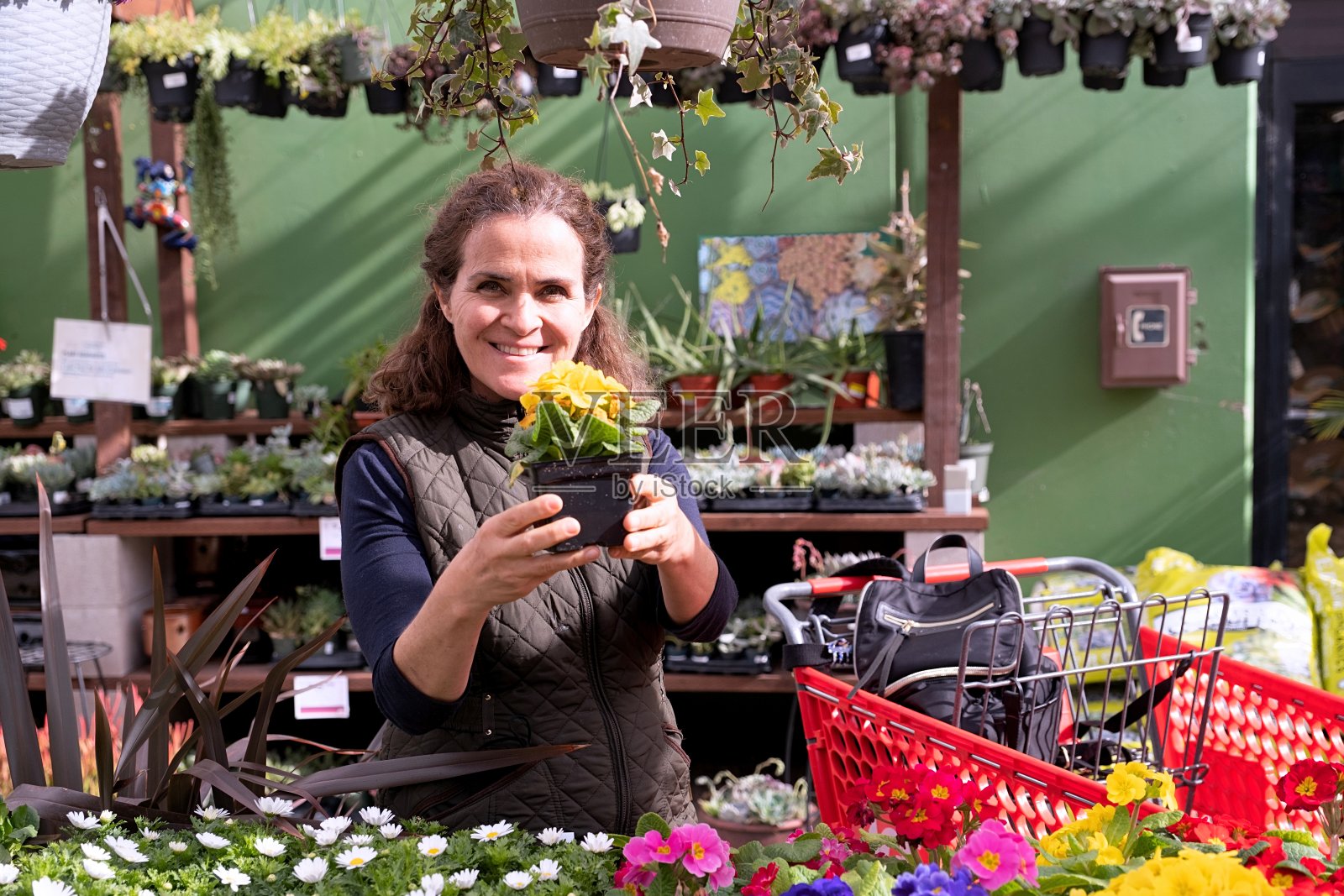 微笑的成熟女人买植物和鲜花照片摄影图片