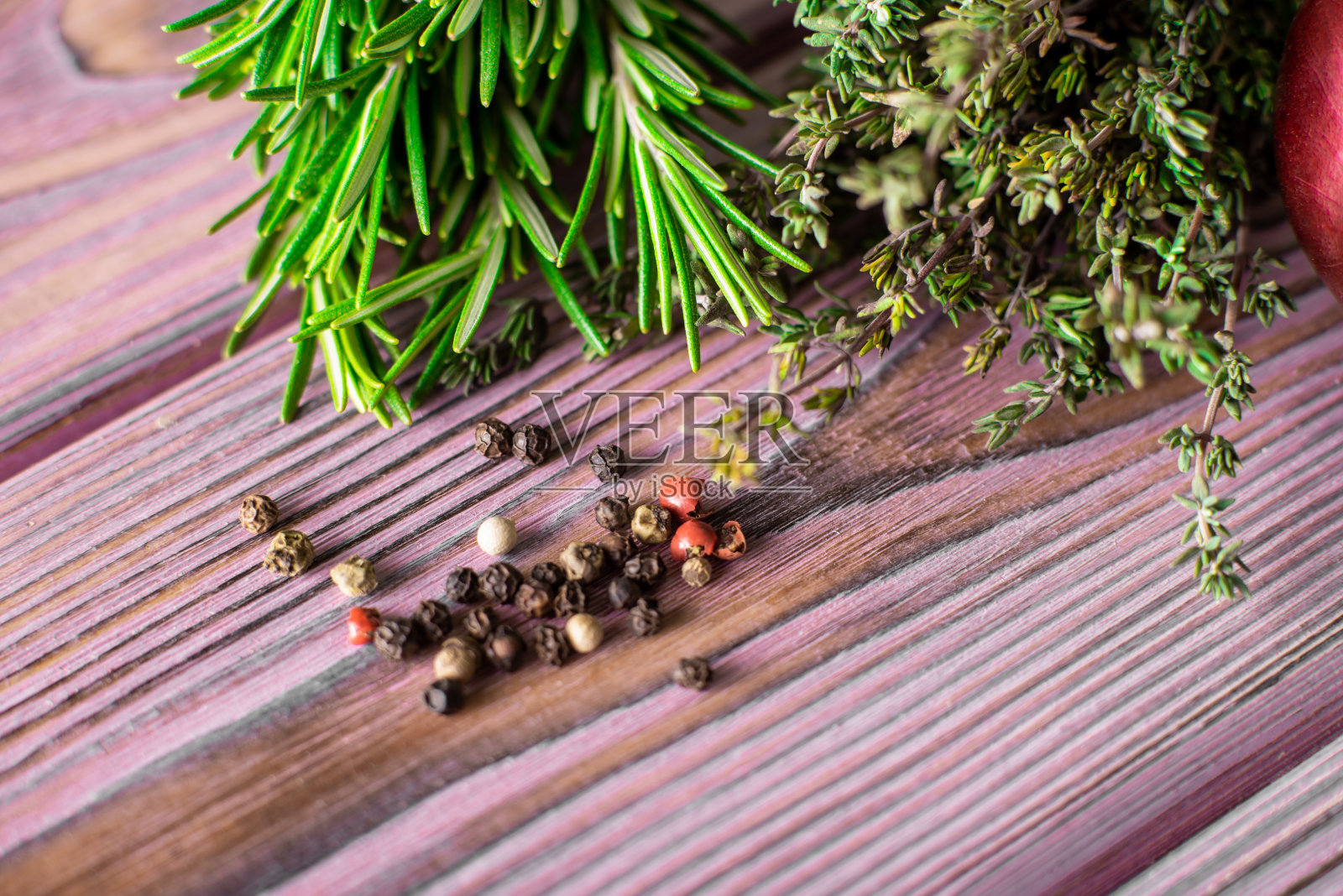 百里香，胡椒，迷迭香在紫色木质底色上。各种各样的香料。照片摄影图片