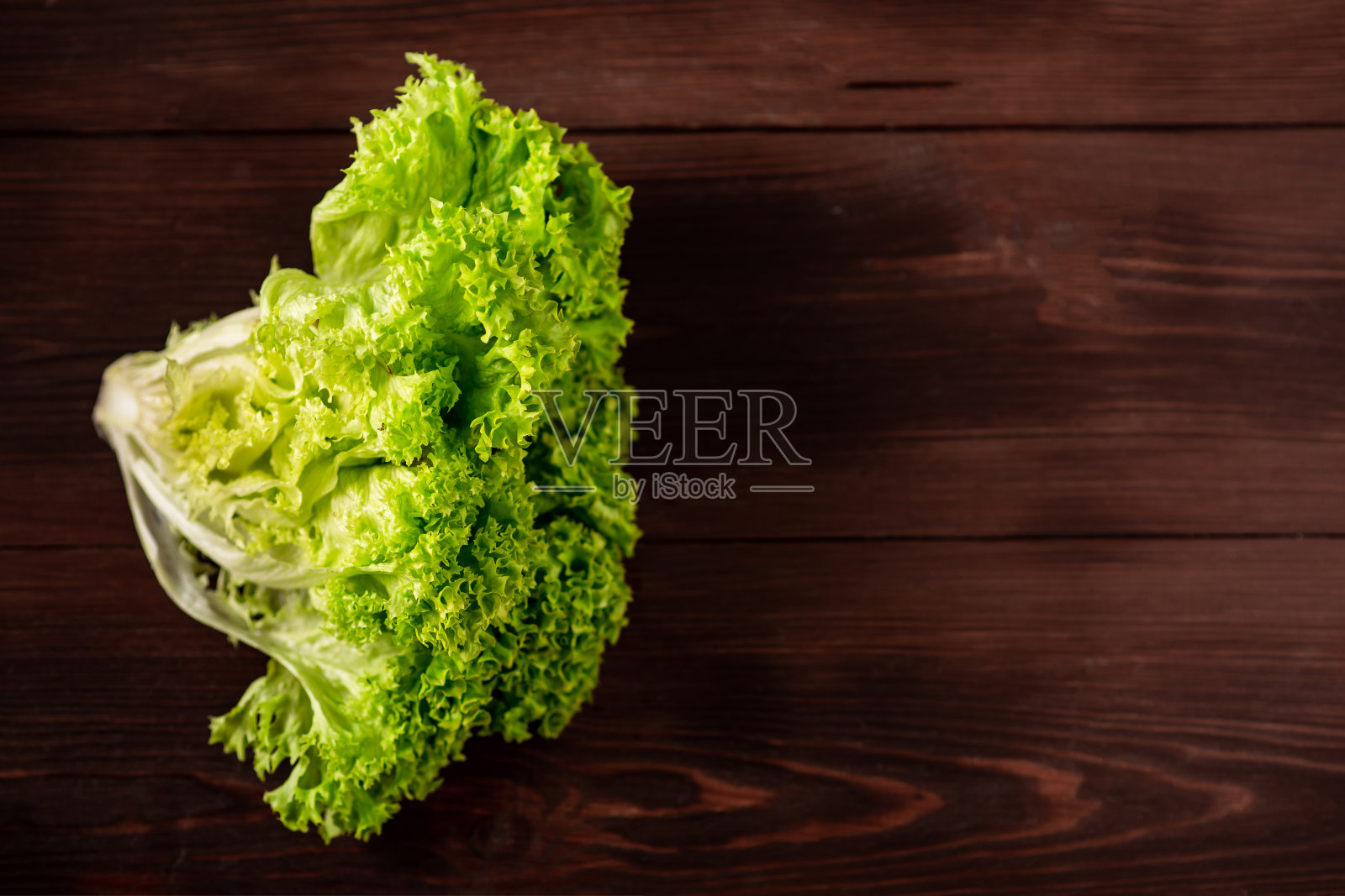 绿色的生菜沙拉在木制的背景。素食观，植物食。文本。照片摄影图片