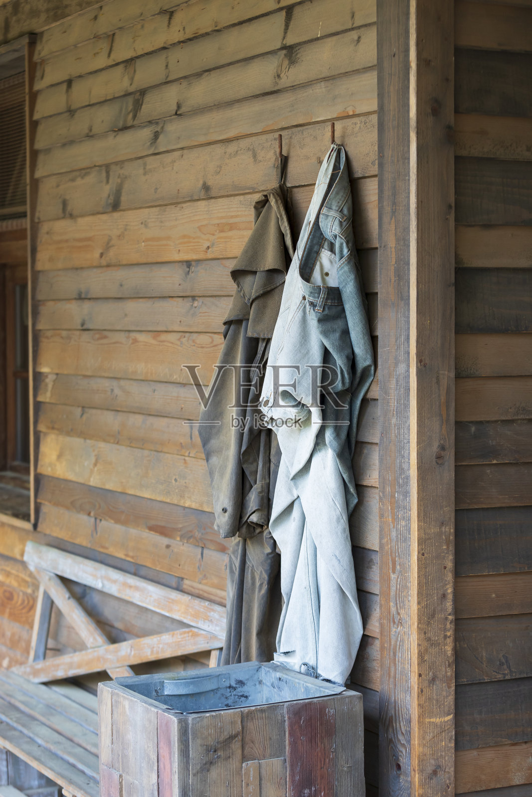 裤子和外套挂在房子的木墙上的衣架上照片摄影图片