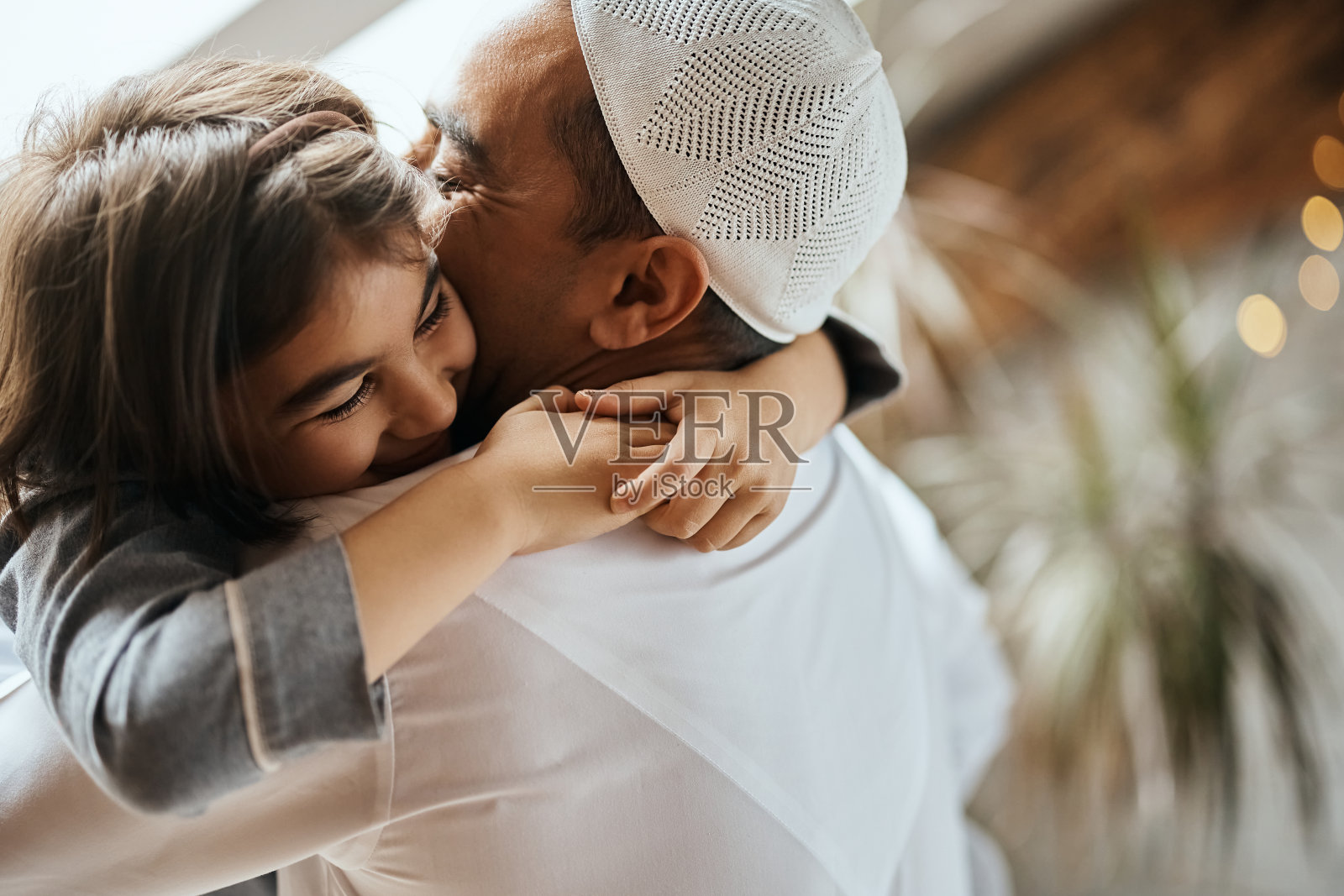 幸福的穆斯林父亲和女儿在家里拥抱。照片摄影图片