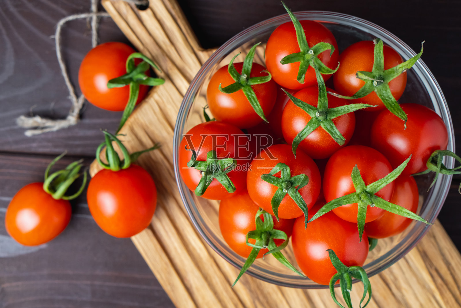 红番茄放在玻璃碗里，放在木桌上的切菜板上。有机健康食品。烹饪原料照片摄影图片