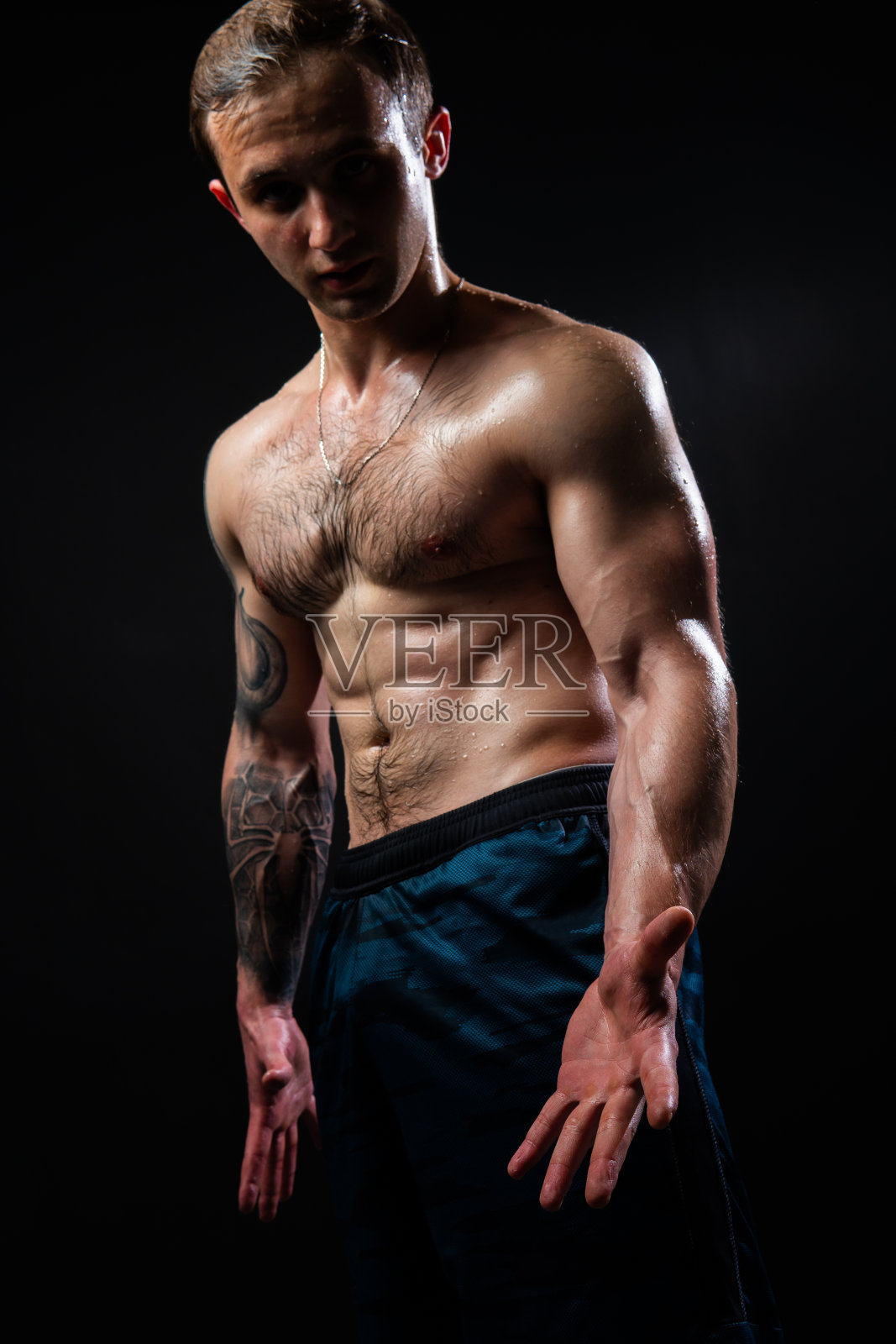 男人在黑色的背景保持哑铃在健身活跃的性感运动，锻炼沉重，健康的胸部。英俊的金属，家伙适合的看法，从下向上良好的压美丽的肌肉毛茸茸的胸部魅力照片摄影图片