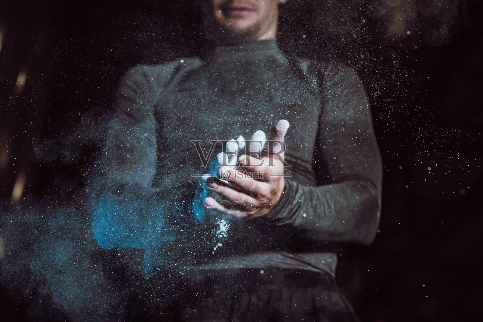 年轻运动员在训练前用粉笔擦手，特写照片摄影图片