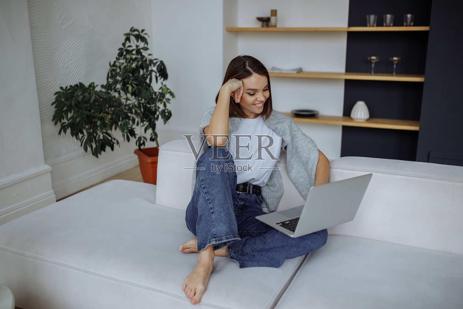 一个小女孩坐在家里的沙发上用笔记本电脑照片摄影图片