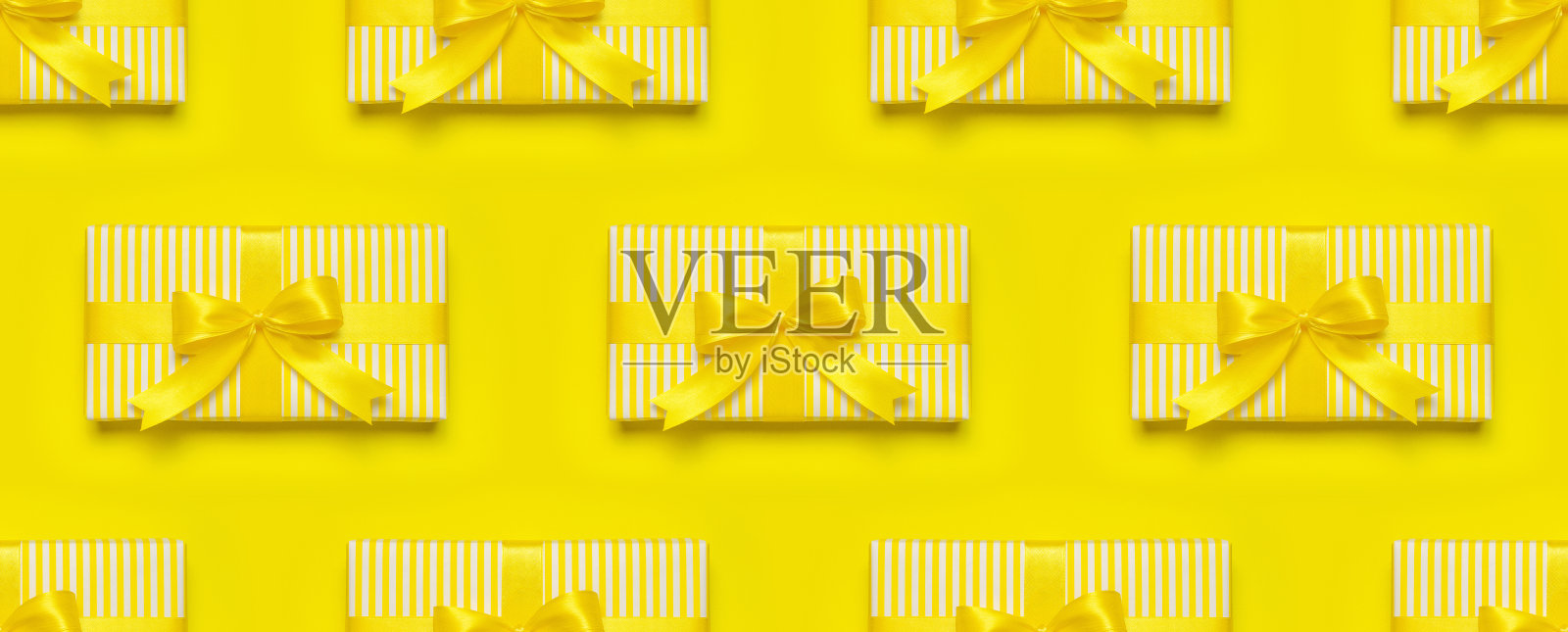 无缝图案的黄色礼品盒与丝带和蝴蝶结在黄色背景顶视图复制空间。平躺假日背景。生日礼物，3月8日，母亲节，情人节照片摄影图片
