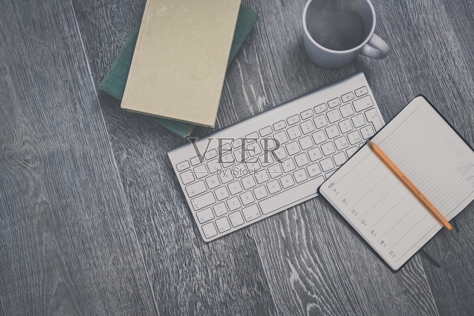 桌面视图与键盘，铅笔，议程和书籍。为智能工作或家庭教育准备的桌子。组织、远程工作、学习、创造力、生产、优柔寡断、观念混乱。照片摄影图片