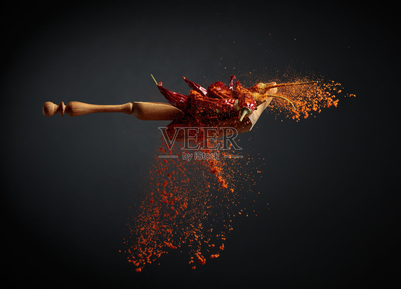 从木勺里倒出胡椒粉。照片摄影图片