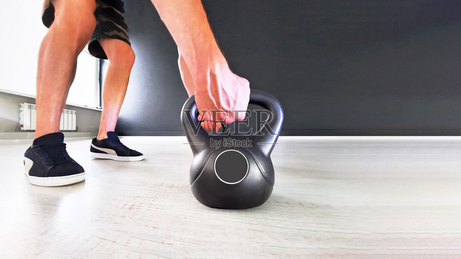 黑色铸铁壶钟在黑色的背景。手拿黑色壶铃照片摄影图片