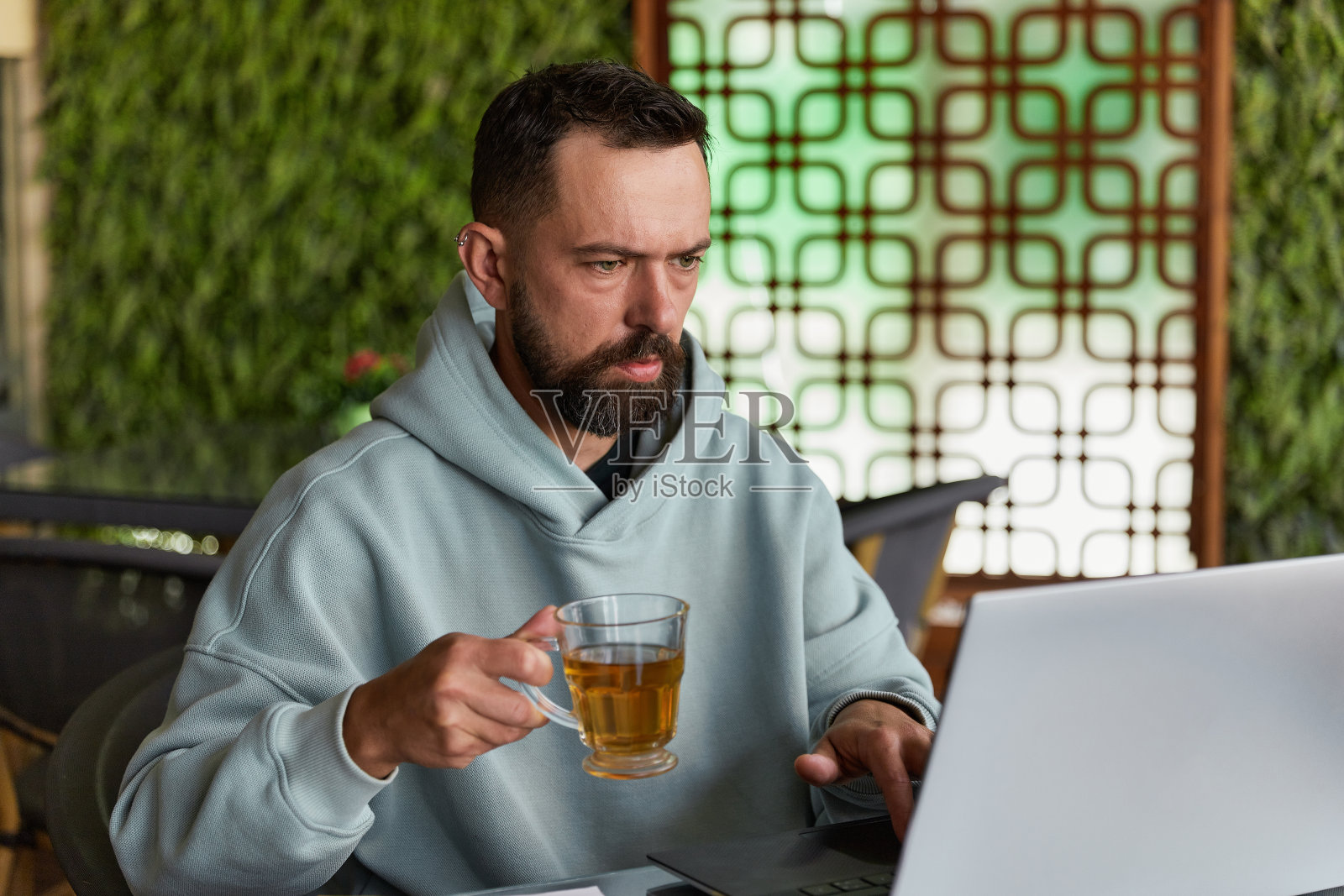 一个穿着便服的大胡子男人在咖啡馆里用笔记本电脑照片摄影图片
