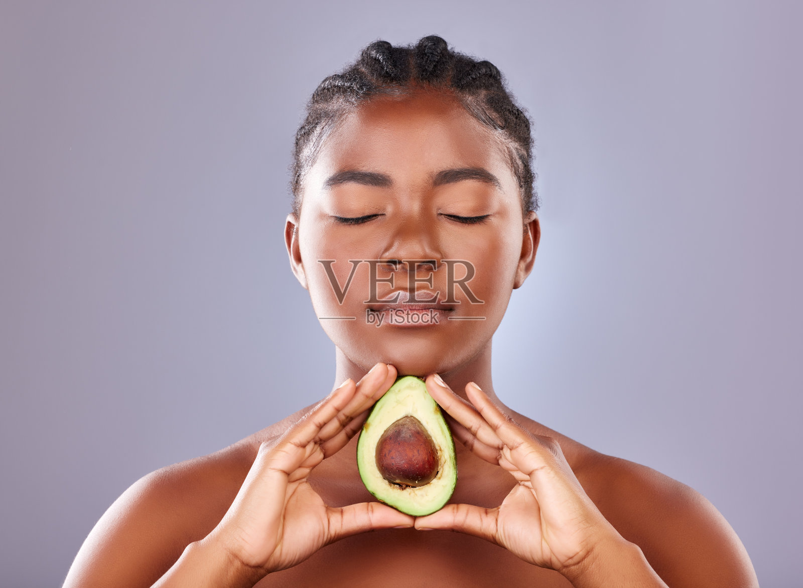 一个年轻漂亮的女人拿着一个切成两半的鳄梨照片摄影图片