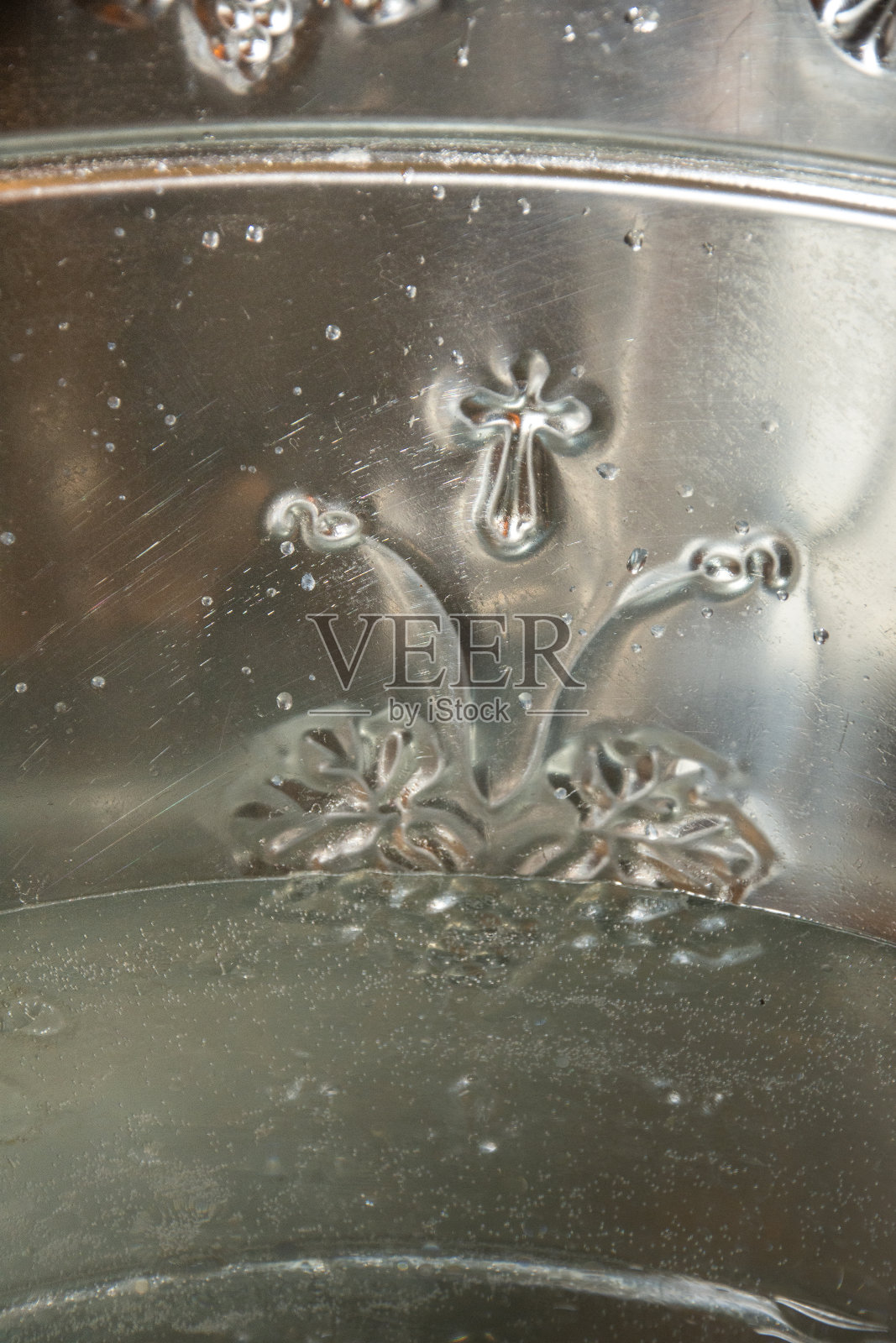 罗马尼亚东正教堂的洗礼仪式上，一个不锈钢容器上印着十字架照片摄影图片