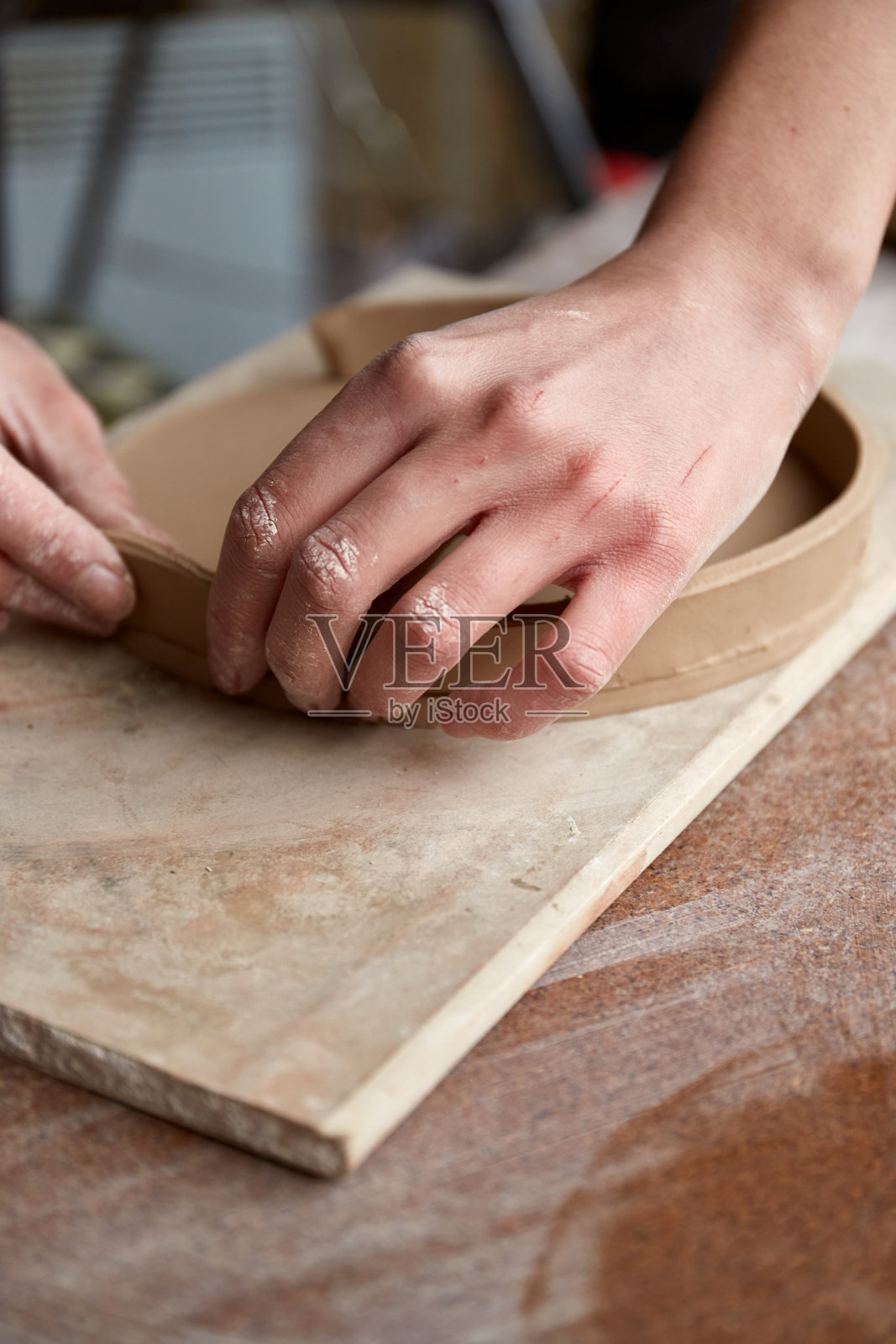 在陶艺工作室工作的女性陶艺家。陶艺家的手沾满了粘土。制作陶器的过程。陶艺大师在她的工作室里工作照片摄影图片
