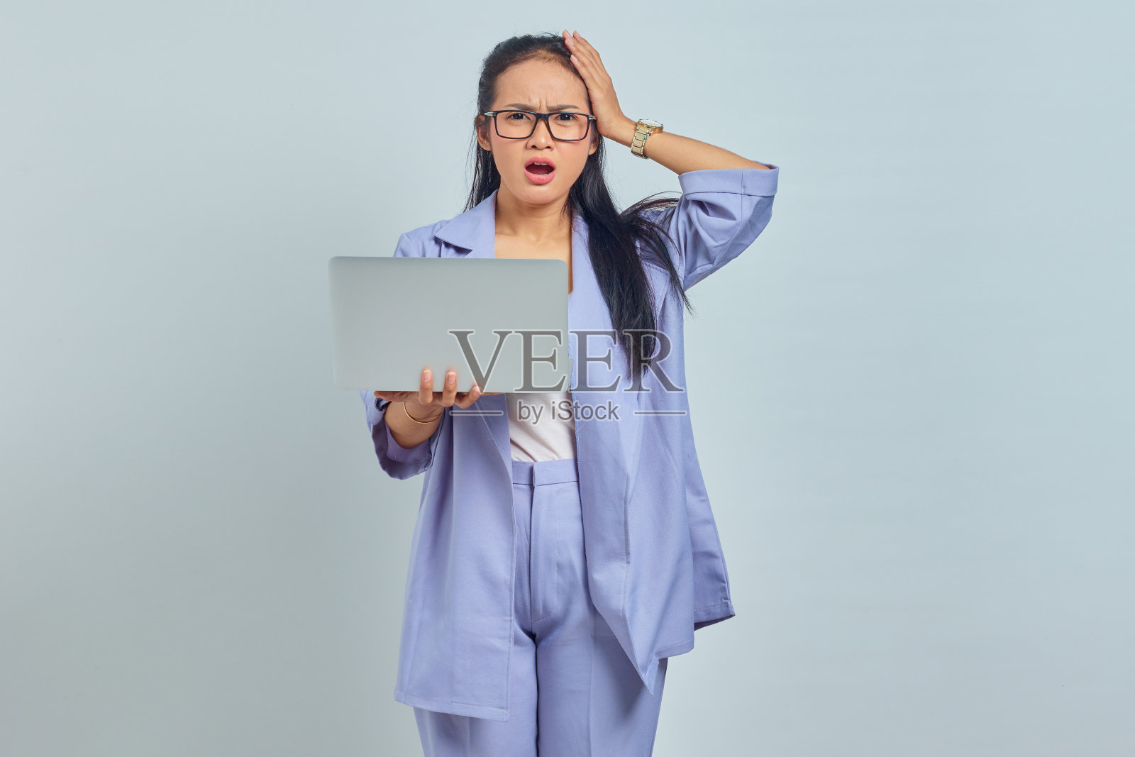 惊讶的年轻亚洲妇女站在使用笔记本电脑和持有头与手掌孤立在白色背景的肖像照片摄影图片