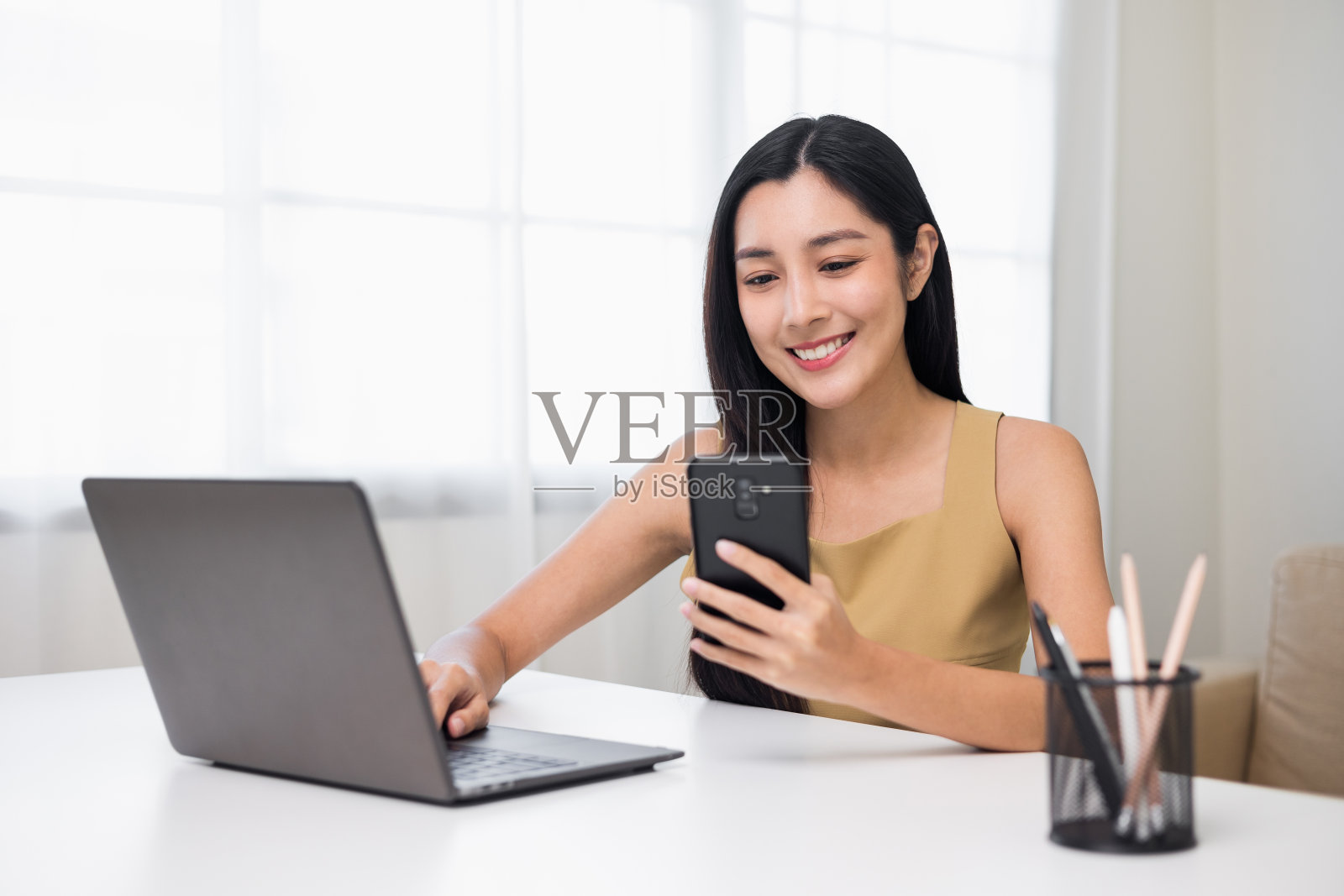 年轻的亚洲妇女使用智能手机聊天视频会议在线坐在客厅在家里。商务女性通过智能手机在线购物。照片摄影图片