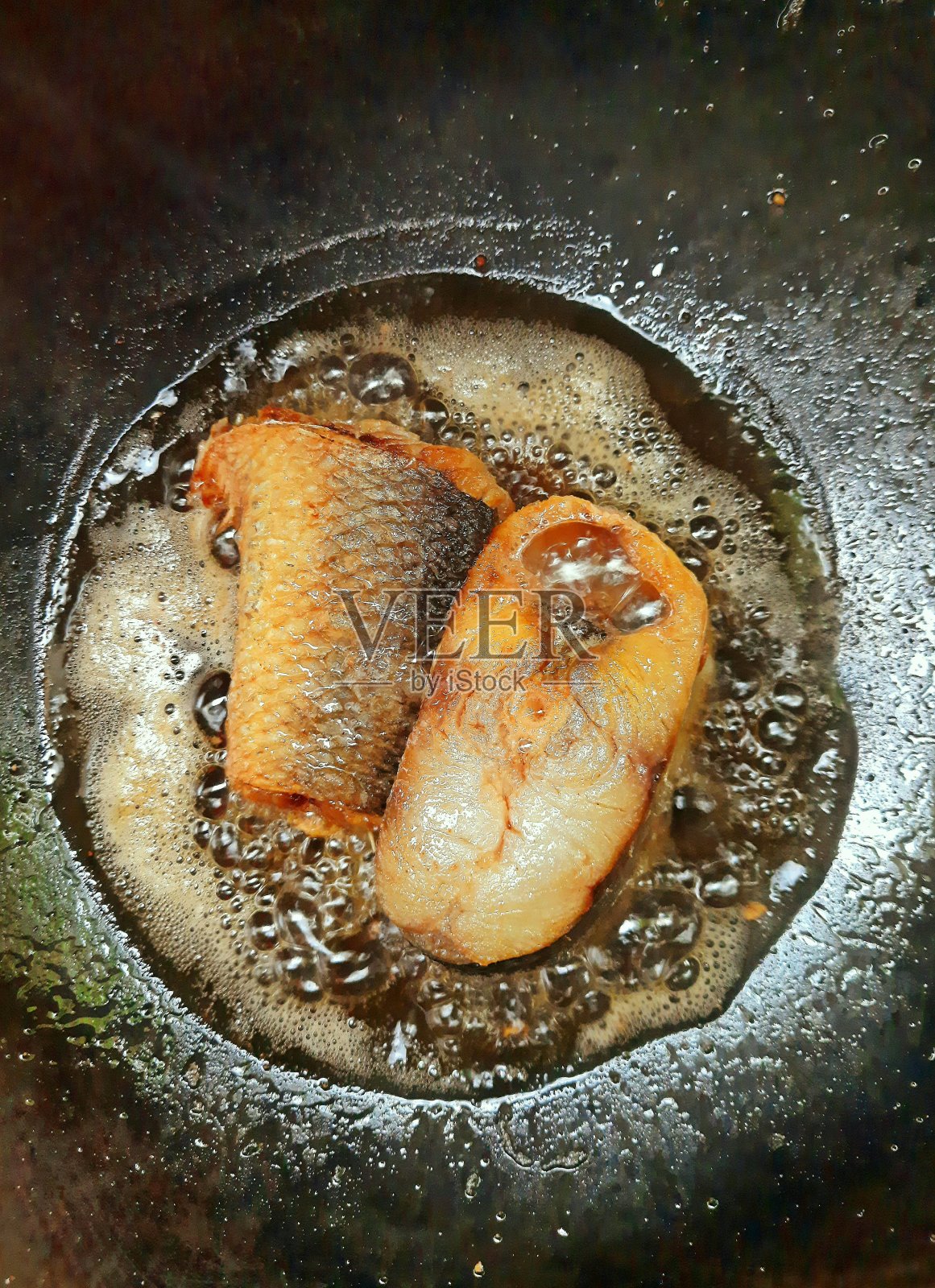 油炸咸鱼在烹调油-食品制备。照片摄影图片