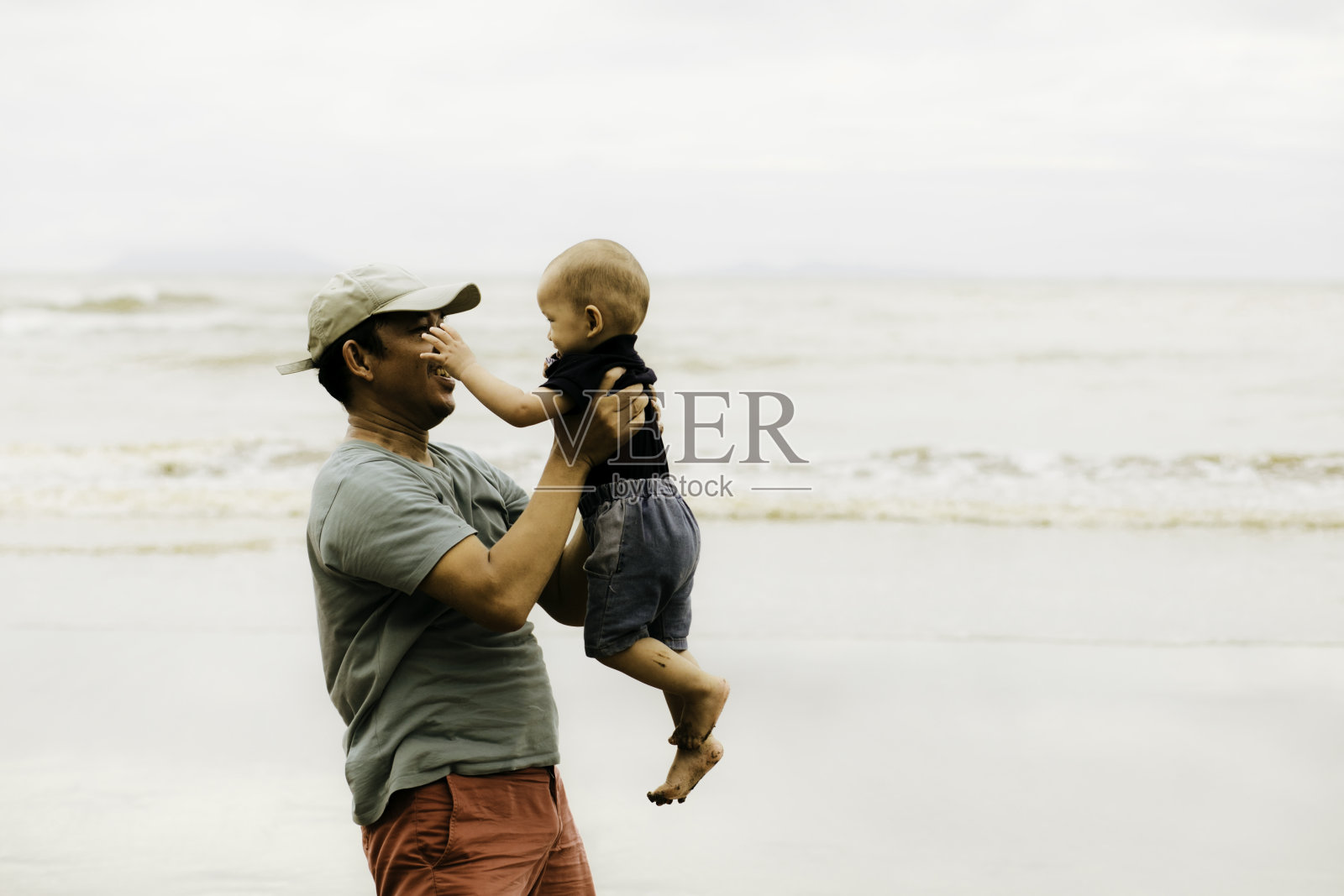 父亲在沙滩上抱着一个小男孩照片摄影图片