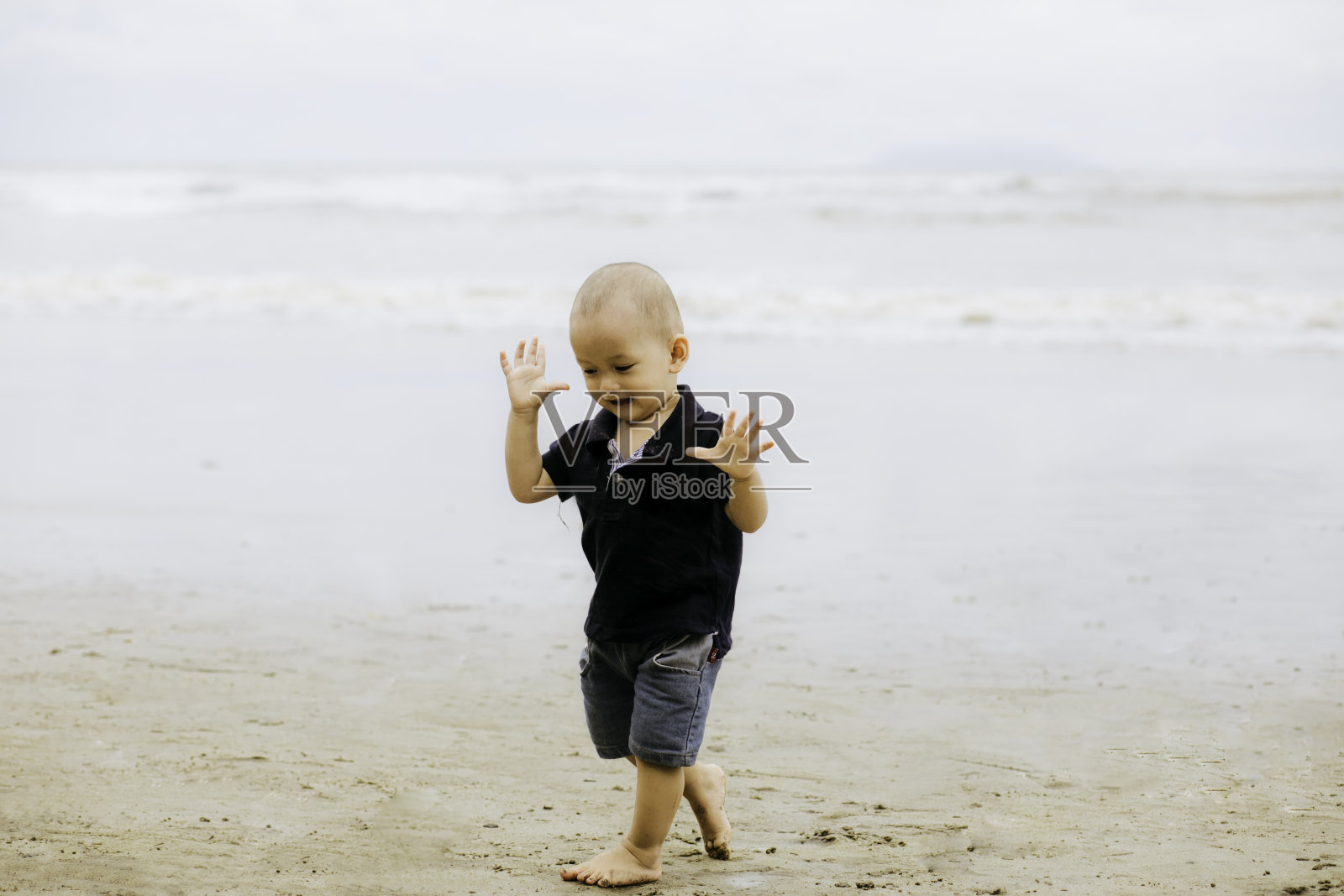 婴儿在海滩上散步，微笑着照片摄影图片