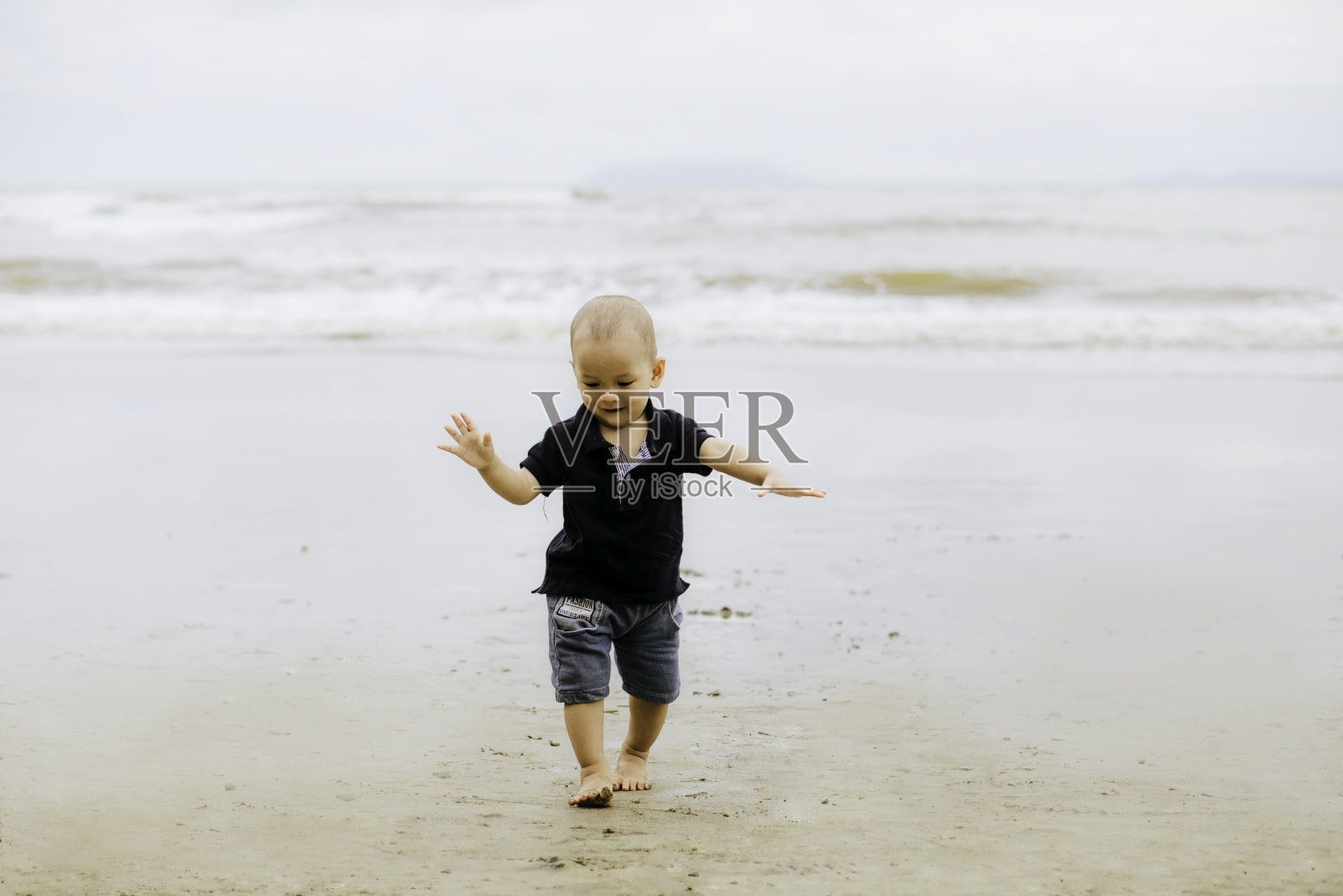 婴儿在海滩上散步，微笑着照片摄影图片