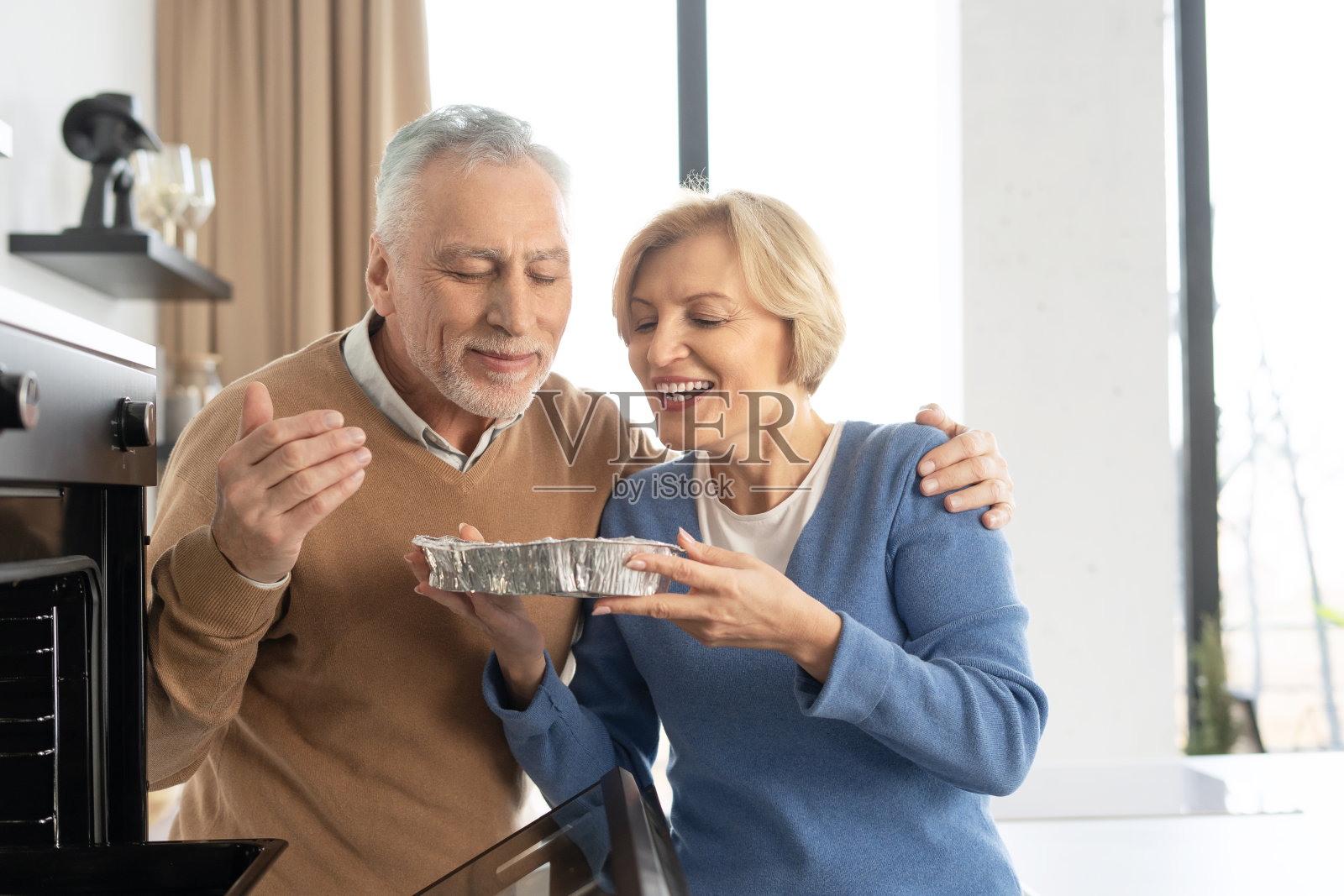 微笑的老夫妇从烤箱里拿菜照片摄影图片