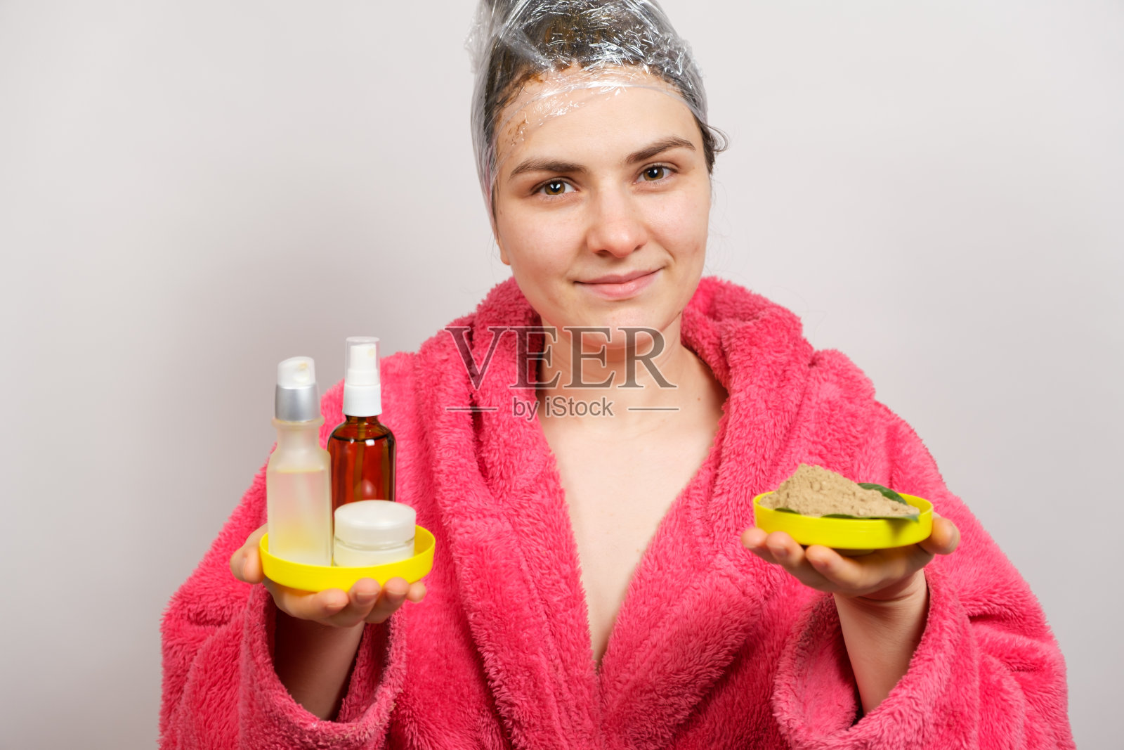 一名妇女头上戴着胶片，制作发膜，手里拿着天然和非天然的化妆品照片摄影图片