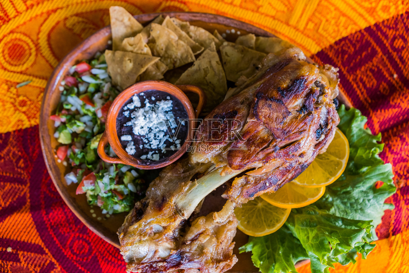 彩色桌布上的烤肉配蔬菜和炒豆照片摄影图片