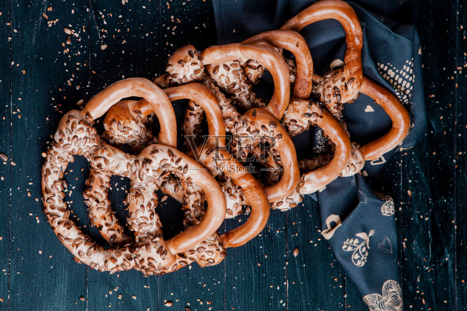 新鲜自制软椒盐卷饼。黑色背景上不同类型的带籽烤百吉饼。照片摄影图片