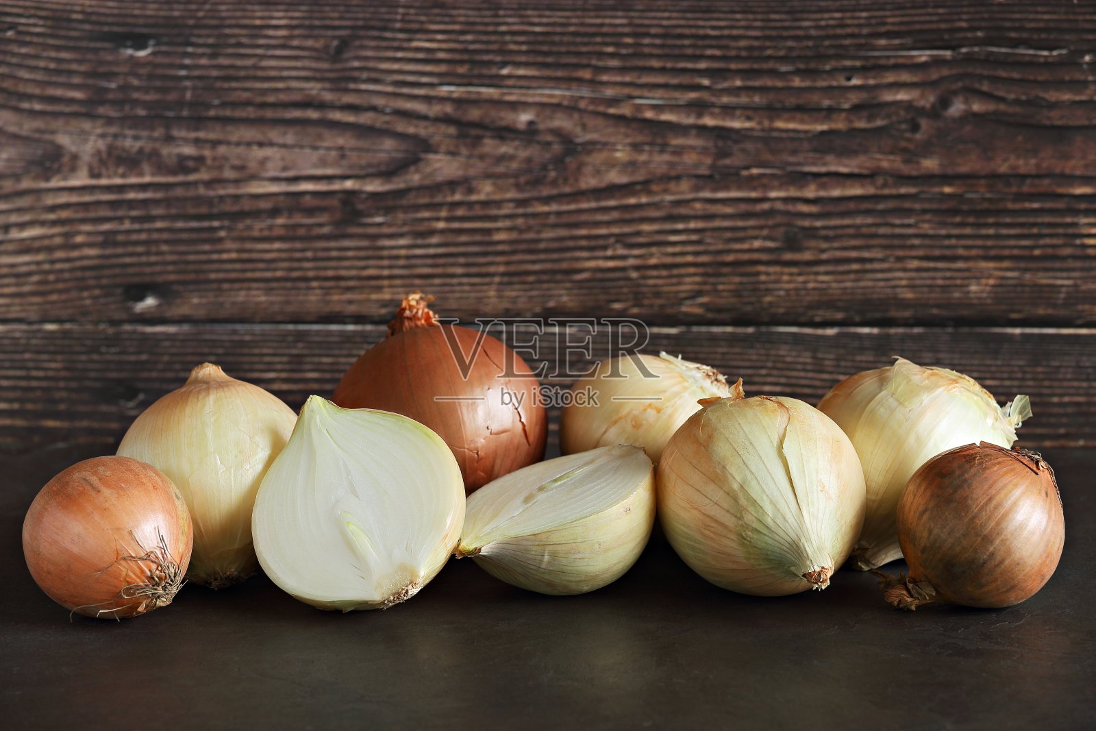 新鲜的一半和整个洋葱在黑暗的木制背景。照片摄影图片