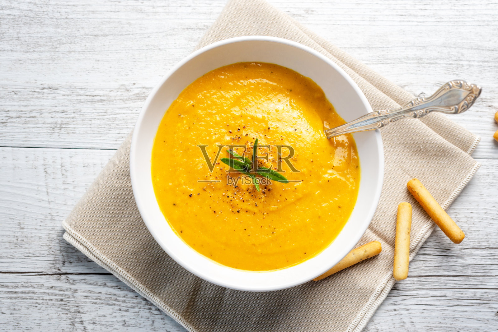 南瓜汤，亚麻餐巾，浅色背景。照片摄影图片