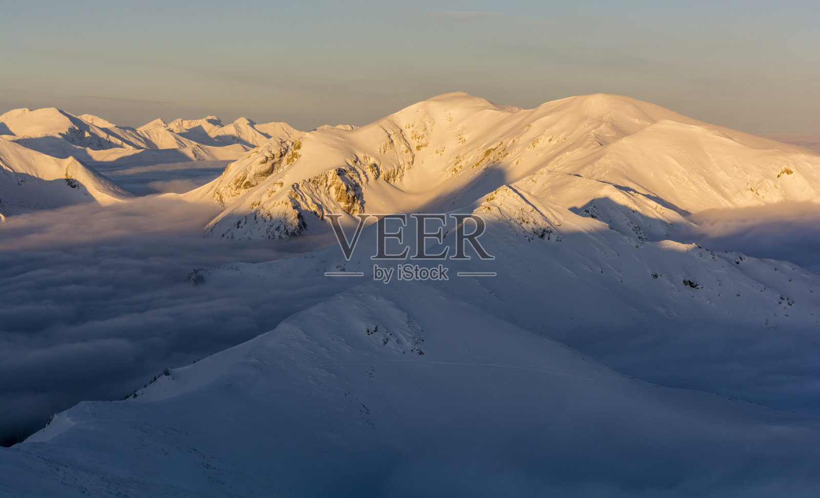 冬日的山峰在黄金时间里沐浴在初升的太阳的光芒中。照片摄影图片