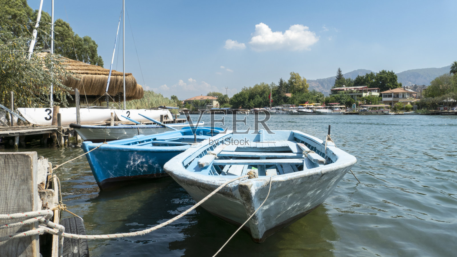 背景中的海滨小镇中心和系柱上的划艇照片摄影图片