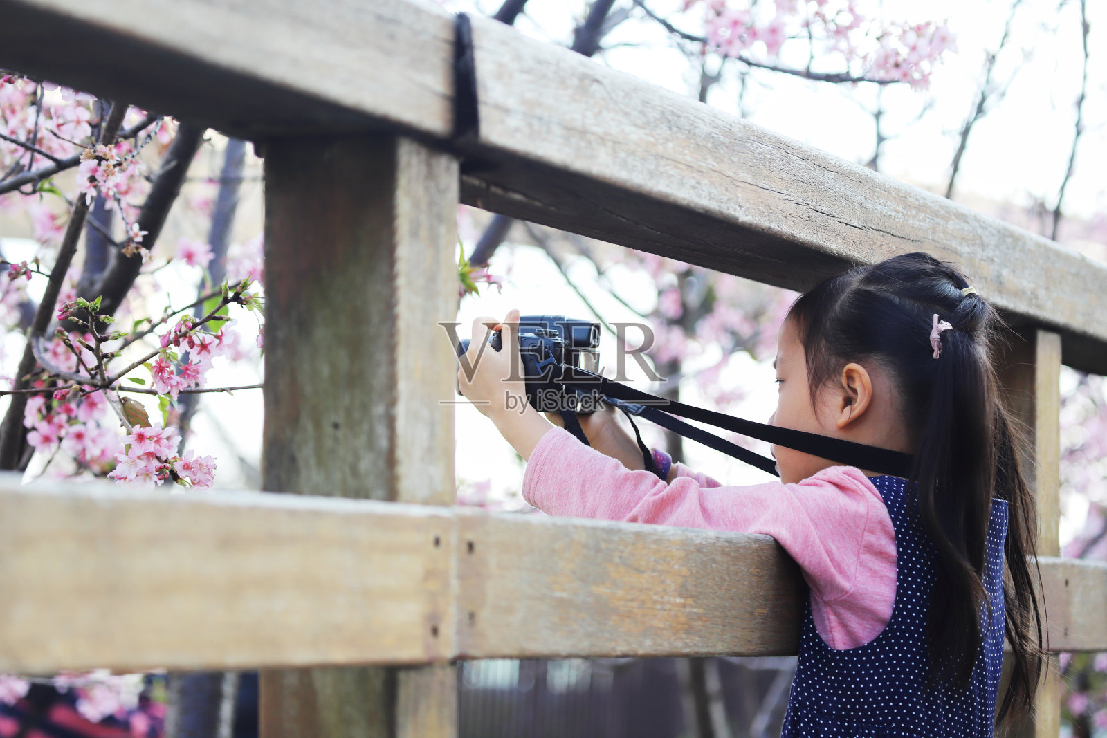 一个亚洲女孩用数码相机拍照。照片摄影图片