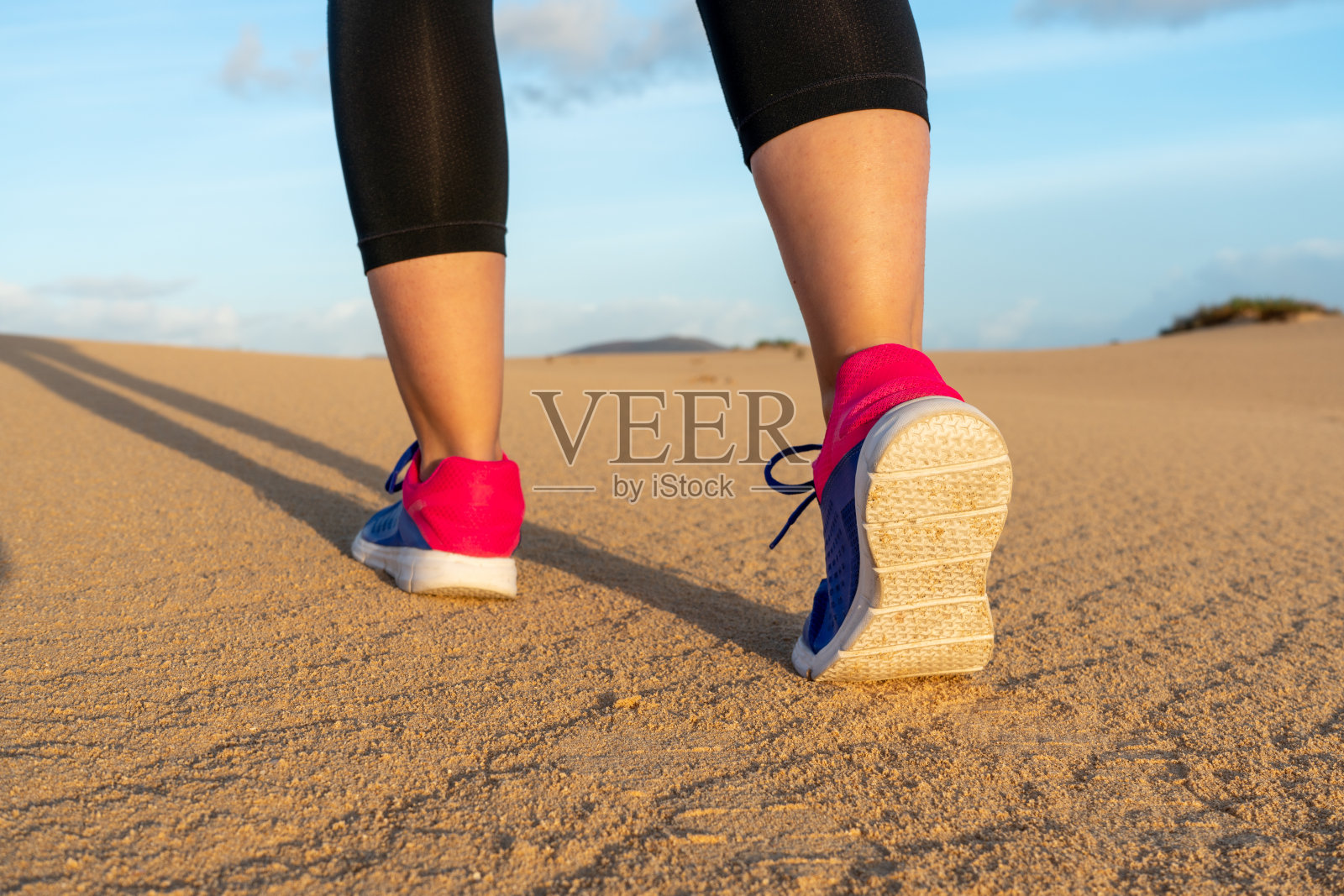 女运动员奔跑在沙丘-选择性的焦点。照片摄影图片