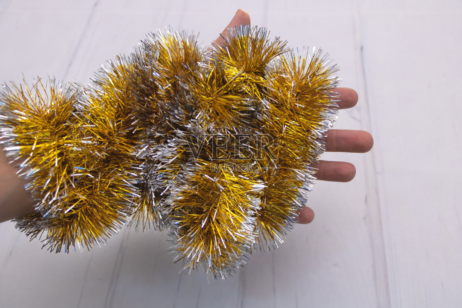 白色的桌子上，金色的圣诞金属丝包裹着一只手照片摄影图片