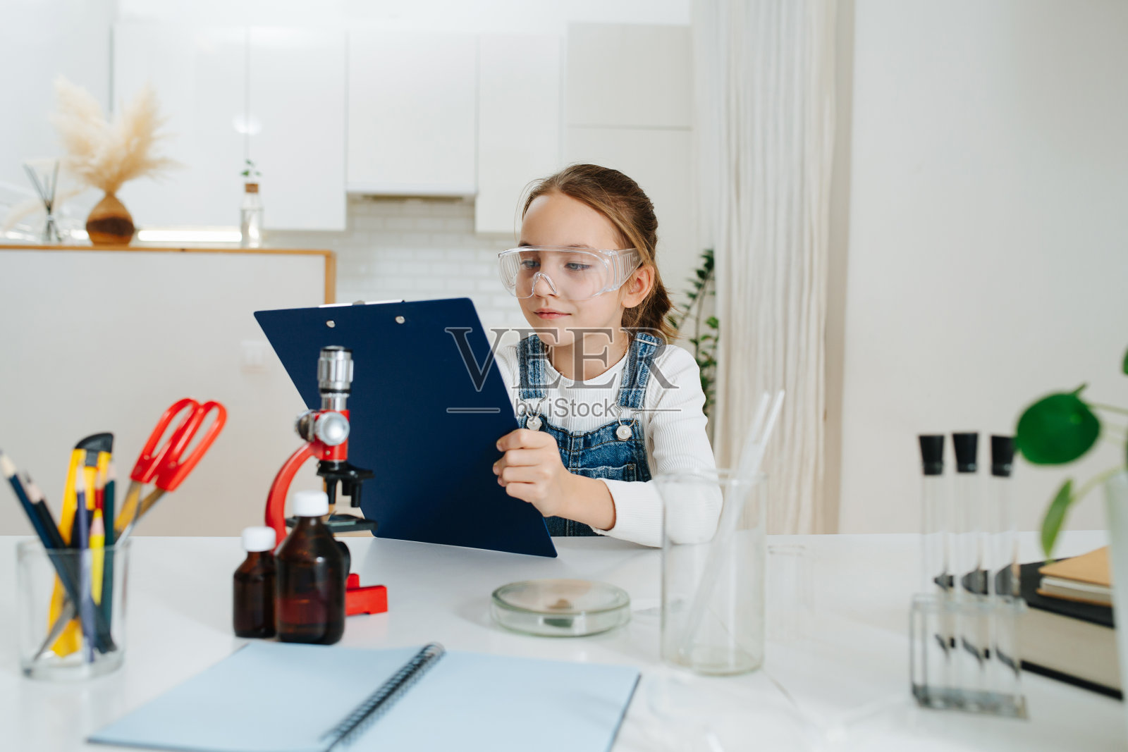 八岁的小女孩想做家庭科学作业，检查她的计划照片摄影图片
