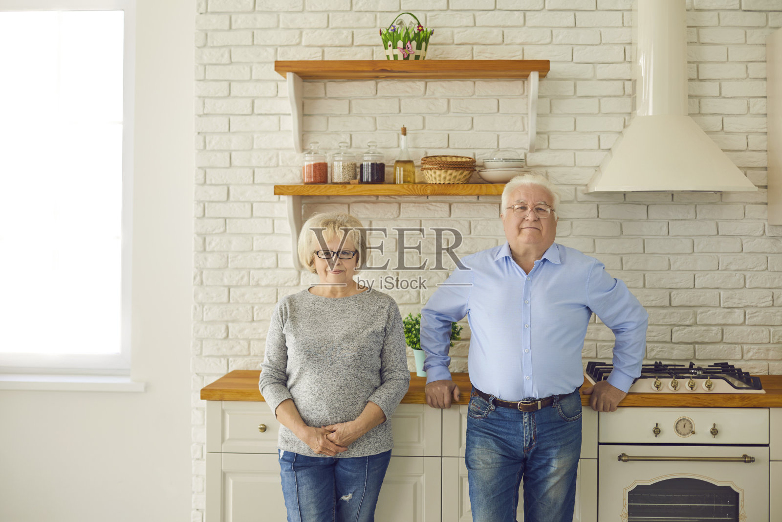 快乐的老夫妇爷爷奶奶站在厨房里看着镜头照片摄影图片