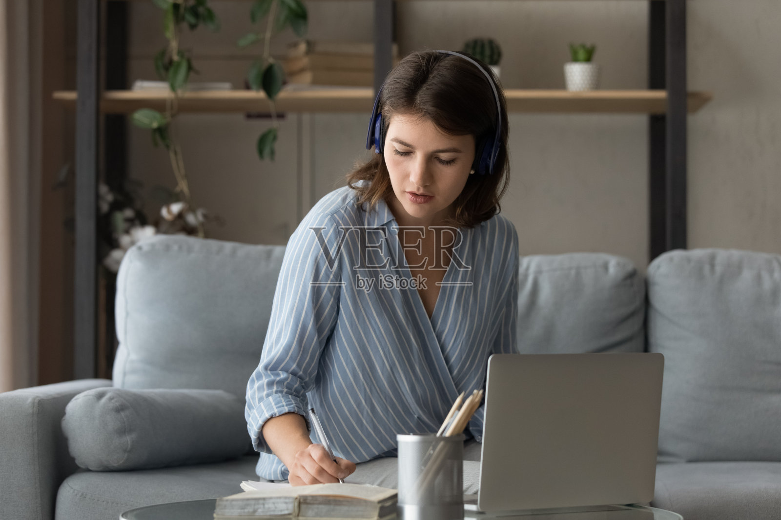认真的年轻成年女学生在耳机听音频研讨会照片摄影图片