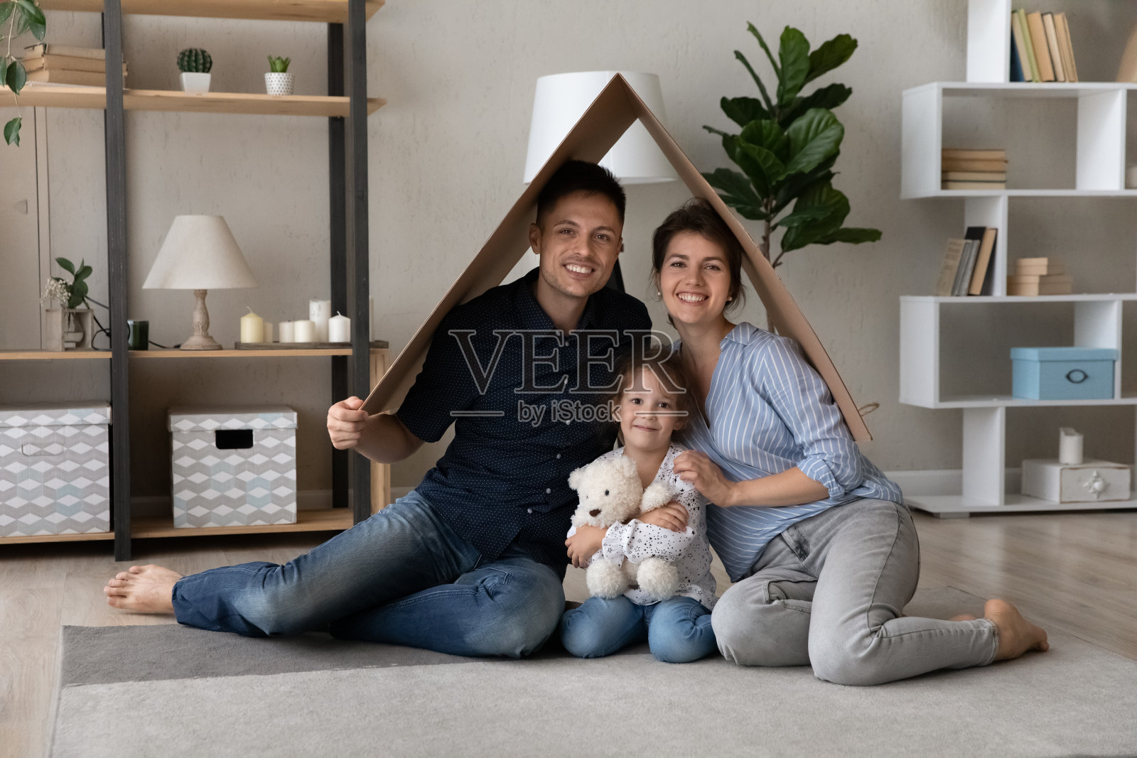 幸福的夫妇和可爱的女儿拿着纸板屋顶照片摄影图片