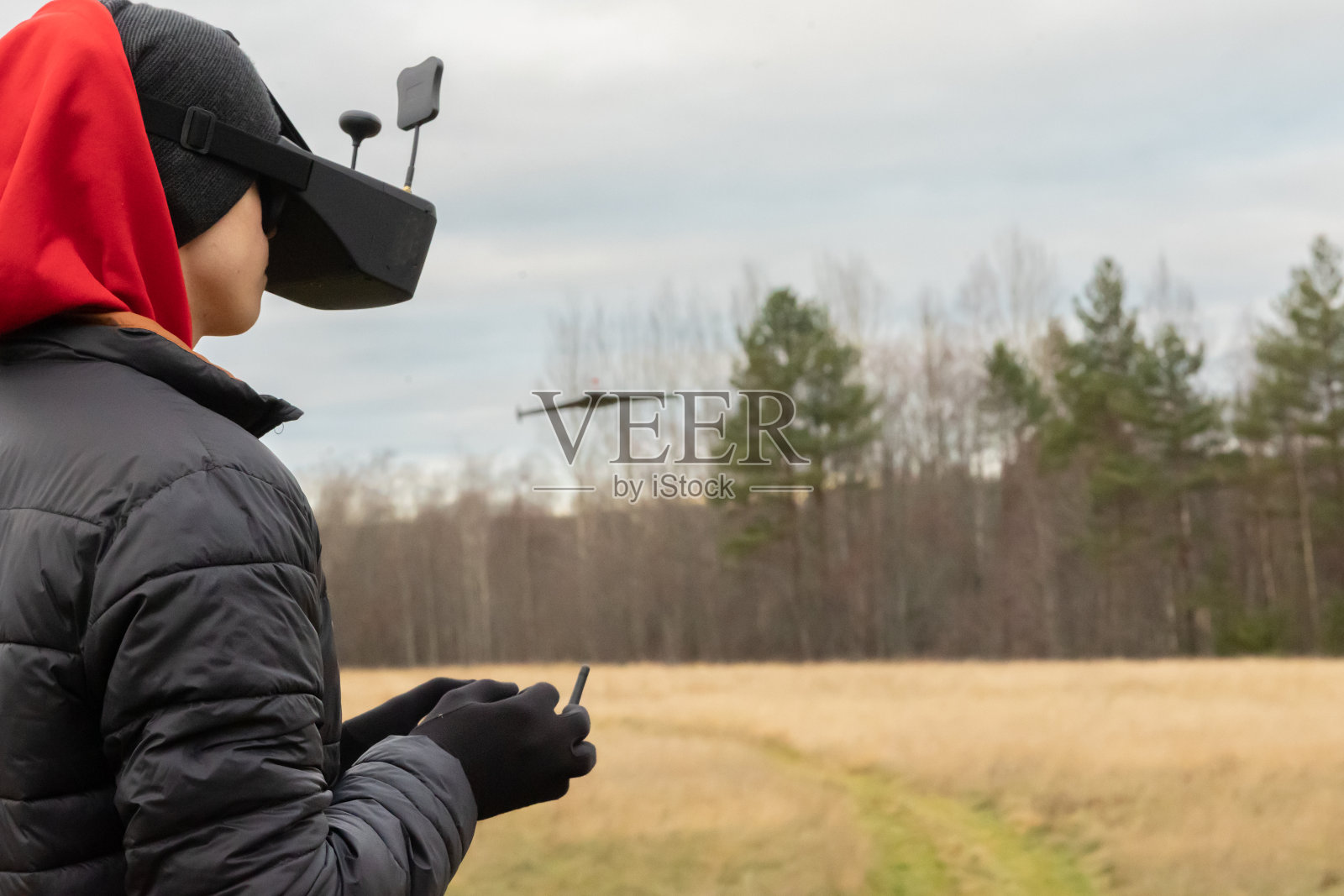 一个年轻人将遥控飞机发射到空中。戴着眼镜的少年在户外玩玩具遥控飞机。男孩拿着无线电遥控器。照片摄影图片