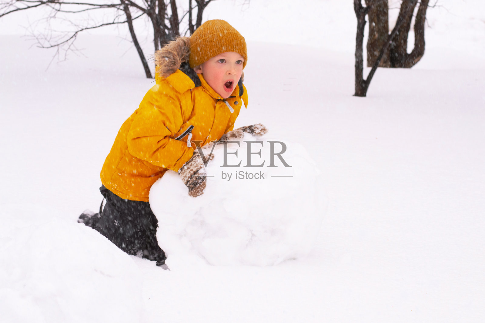 男孩正在堆雪人照片摄影图片