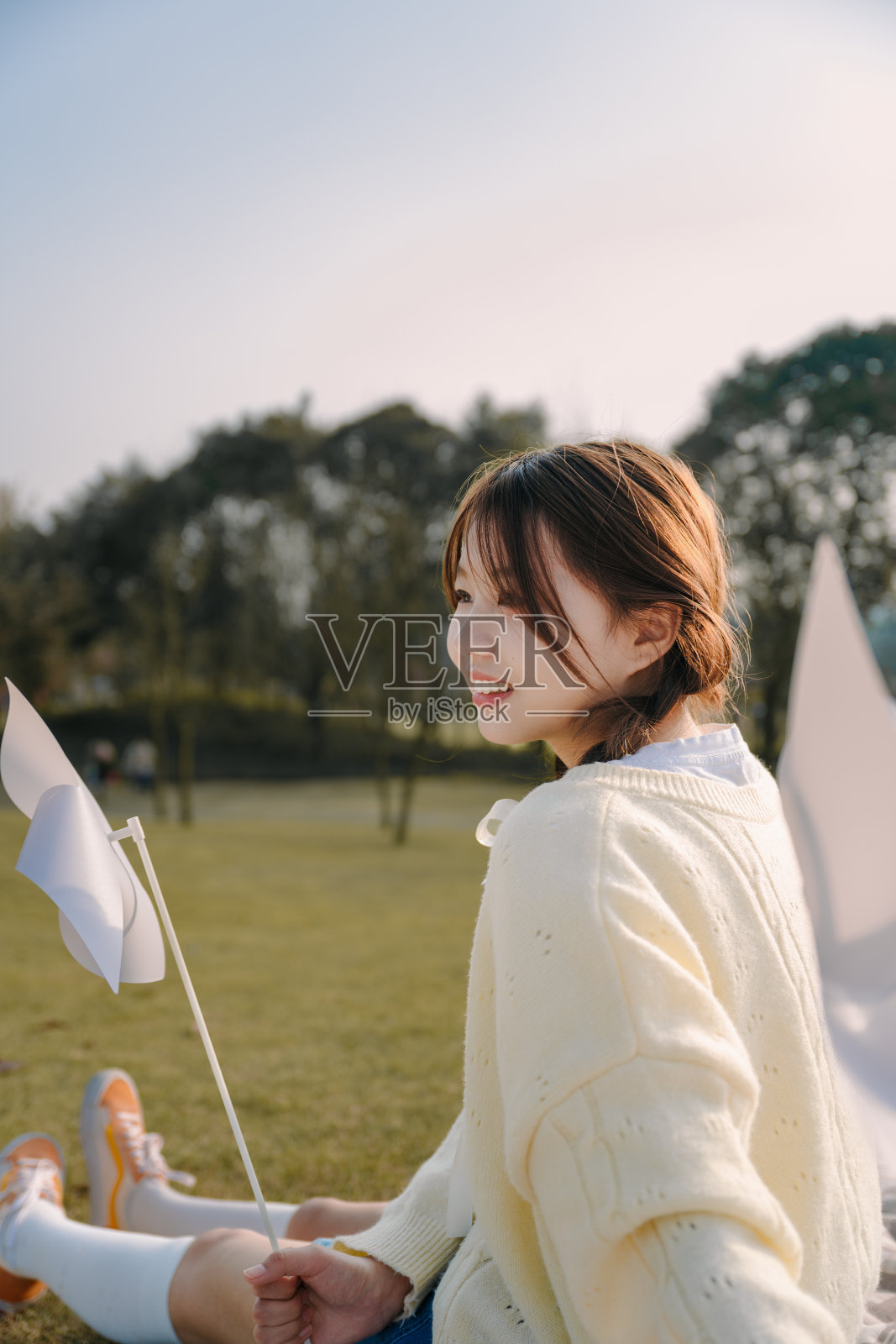 一个美丽的亚洲女孩和一个纸风车在黄昏的草坪上照片摄影图片