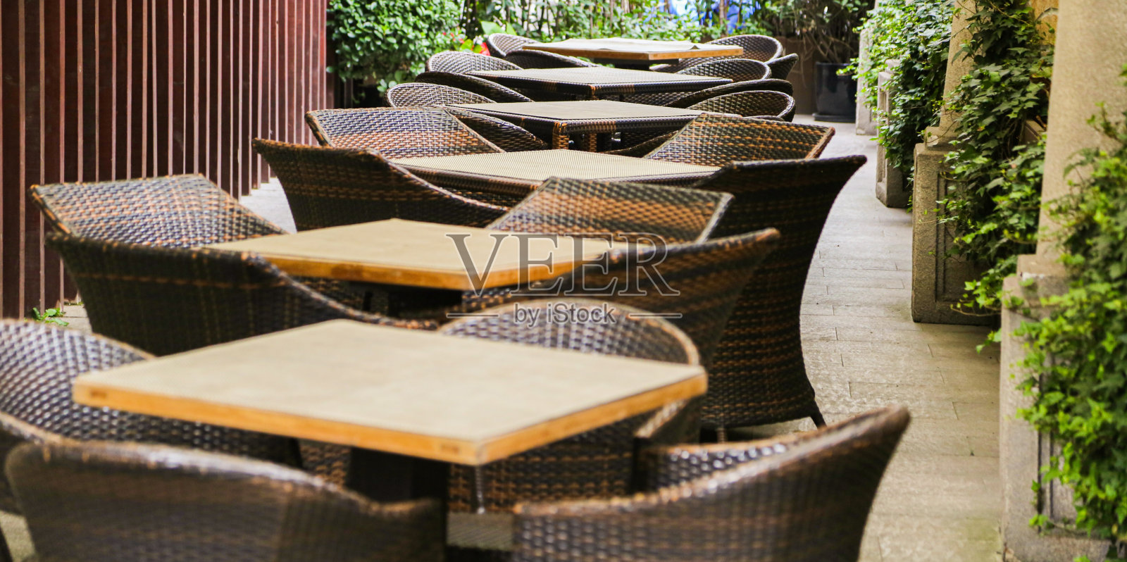 木桌和藤竹扶手椅在空的餐厅户外露台石柱和砖地板照片摄影图片