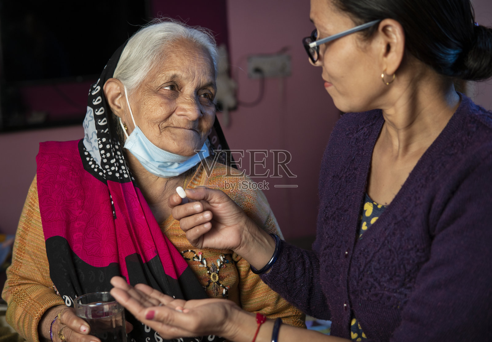 印度女儿在家给年迈的母亲喂药。照片摄影图片
