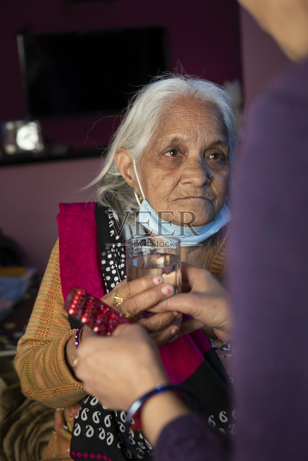 印度女儿在家给年迈的母亲喂药。照片摄影图片