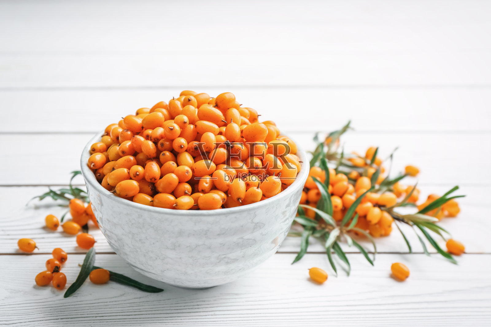 新鲜成熟的沙棘碗，白色木桌上照片摄影图片