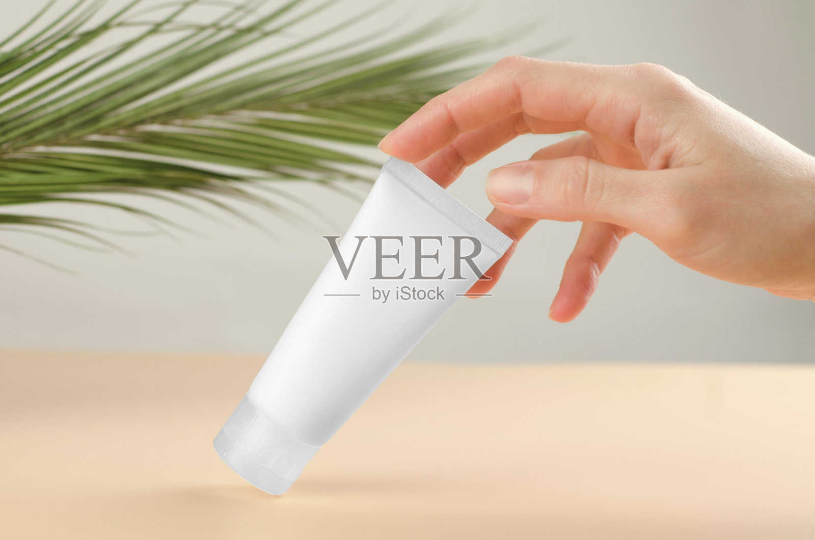 为身体护理的天然化妆品。用手触摸涂有保湿霜的化妆管。照片摄影图片