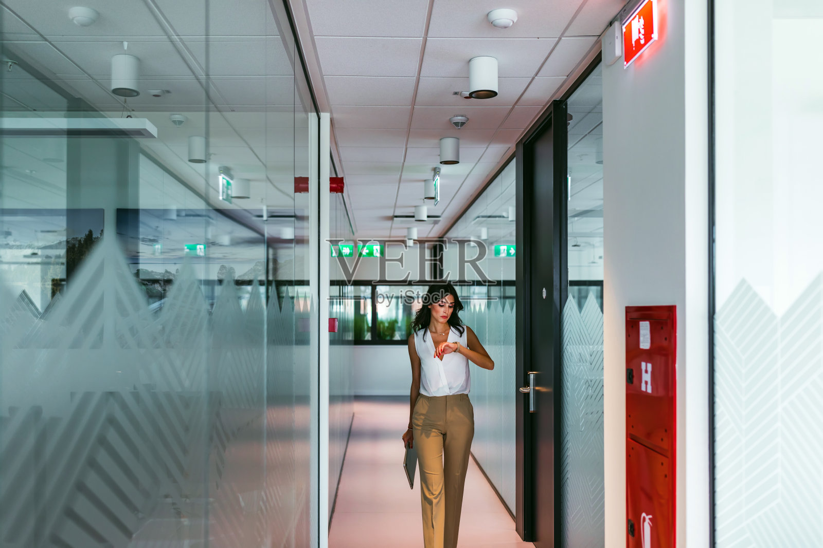 年轻的女商人在办公室走廊里行走照片摄影图片