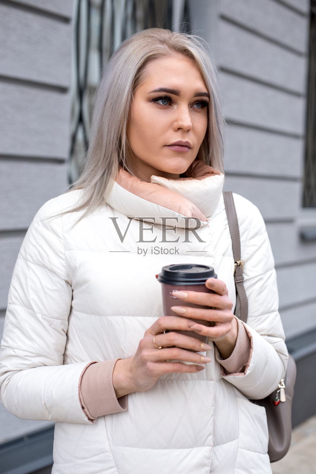 垂直的金发体贴的女人，等待朋友的陪伴，工作日后的咖啡休息，寒冷的天气。近距离照片摄影图片