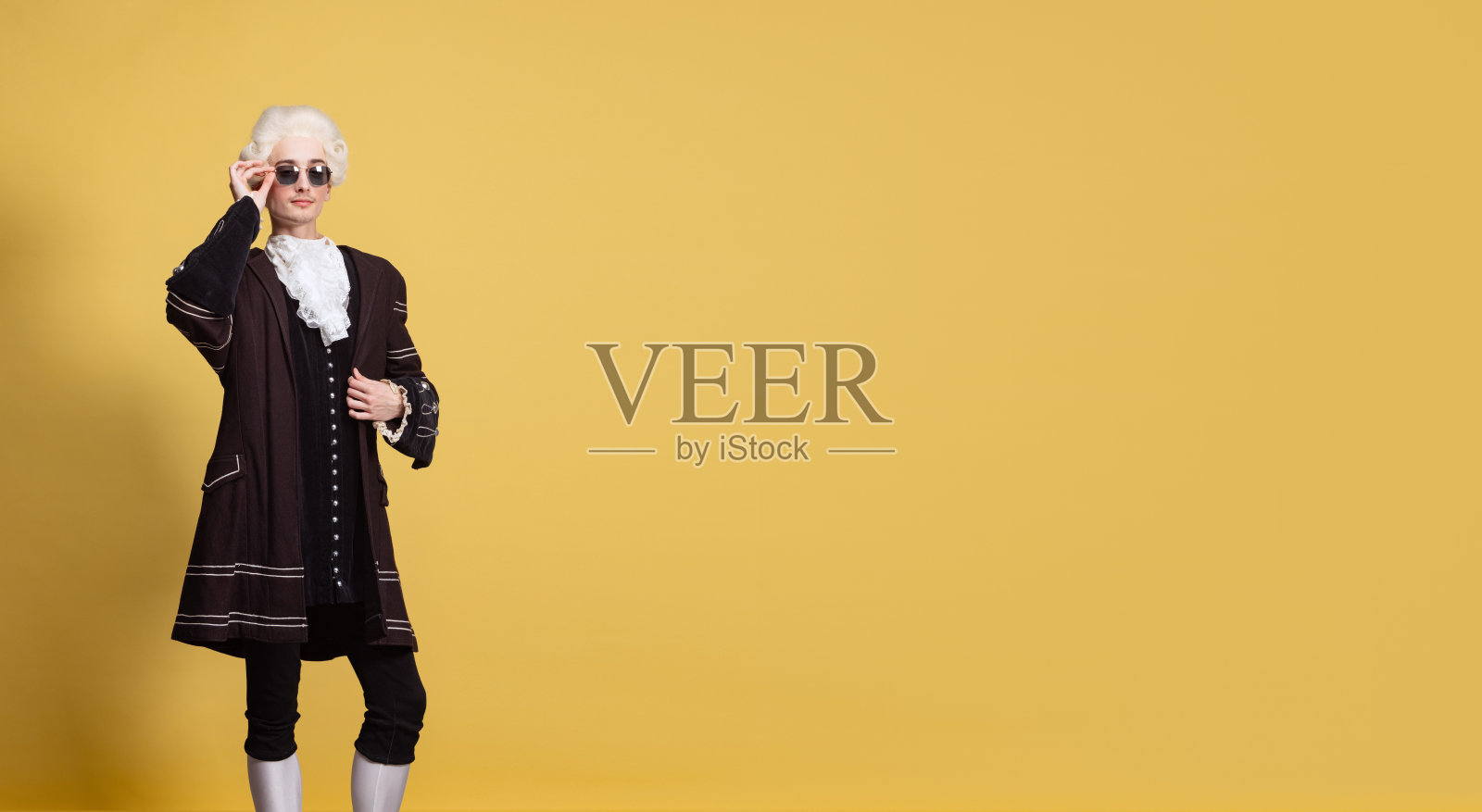 年轻优雅的男子的肖像，白色假发和复古中世纪服装摆孤立在黄色背景。艺术,美丽,时尚照片摄影图片