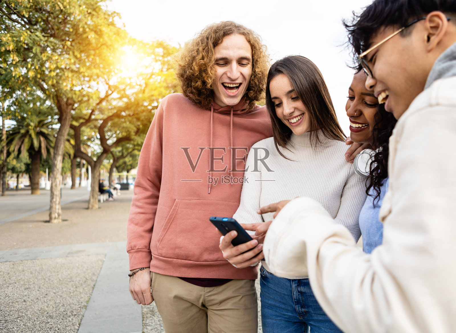 开心的朋友们在智能手机上看搞笑视频时开怀大笑照片摄影图片